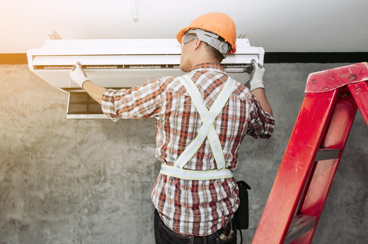 Air technician in the standard set of safety Checking the quality of the newly installed air conditioner.