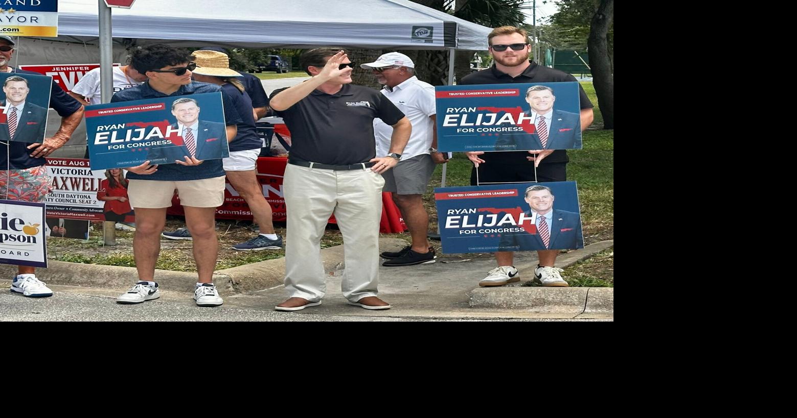 Congressional candidate Ryan Elijah, center, waves to voters at the New Smyrna Beach Regional Library during the Florida primary