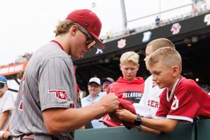 Oklahoma's Nick Wesloski (37) autographs a ball for a young fan before game one of the College World Series championship series against North Carolina at Charles Schwab Field in Omaha on Saturday, June 20, 2026.