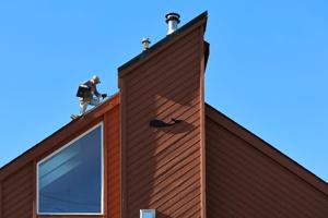 On October 7, 2026, a roofer removes shingles from a house in New Bedford, MA that features a whale decoration, before putting