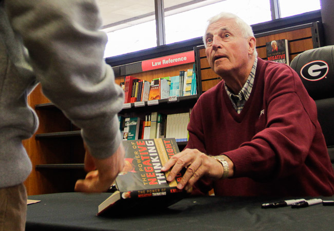 Former college basketball coach Bobby Knight, left, autographs baseballs  while wearing the St. Louis Cardinals colors before their game against the  New York Mets in a spring training Grapefruit League baseball game