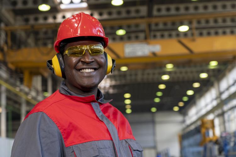 Smiling Young African American Worker In Personal Protective Equipment Looking At Camera