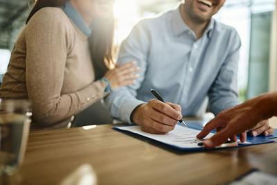 Close up of unrecognizable couple signing a contract in the office.