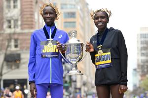 2026 men's and women's champions John Korir and Sharon Lokedi of Kenya pose with the winners cup at the 130th running of the Boston Marathon.