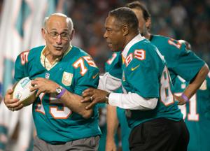 Manny Fernandez jokes with Nat Moore during a halftime ceremony honoring the top 50 players in Dolphins history at Sun Life
