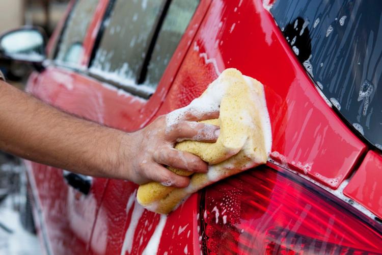 Handwashing a red car with soap and sponge