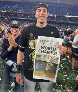 The Milwaukee Brewers Milwaukee Brewers designated hitter Christian Yelich (22) holds up a Milwaukee Journal Sentinel “World