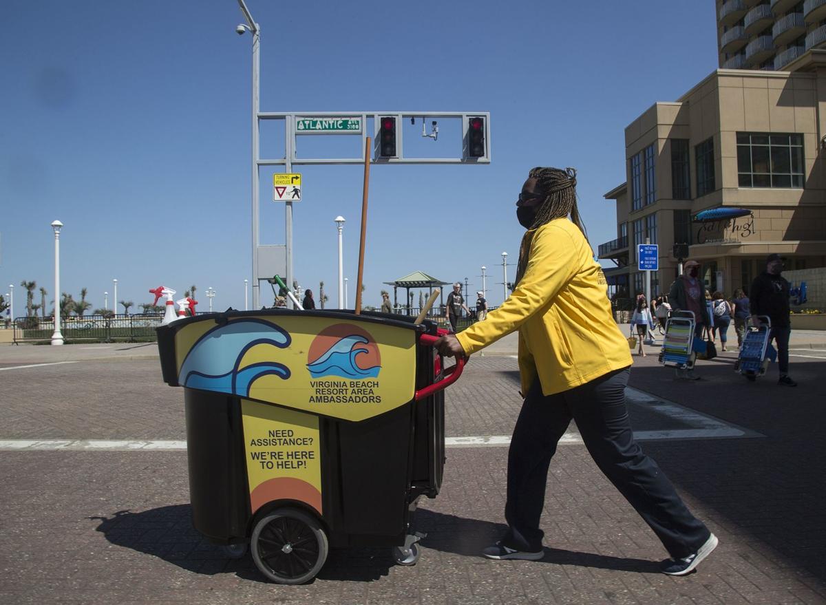 Lateeka Walker pushes a cleaning bin across the intersection of Atlantic Avenue and Laskin Road while working with the Virginia Beach Resort Area Ambassadors on Monday, April 5, 2021, in Virginia Beach, Va.