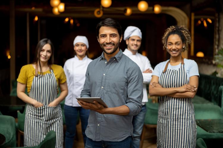Portrait of a business owner smiling with his staff at a restaurant