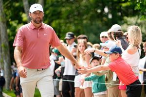 Scottie Scheffler shares a moment with a young fan as he walks to the third tee during the third round of the 2025 Memorial