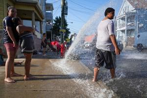 Paterson residents look on while playing in the water from a fire hydrant, Jul 28, 2025, Paterson, NJ, USA.