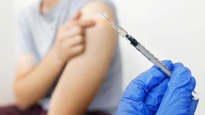 Syringe with vaccine in doctor hand on background of man with coronavirus vaccine injection.Covid-19