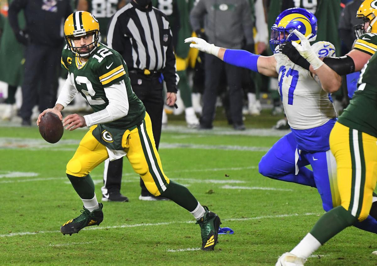 Green Bay Packers quarterback Aaron Rodgers looks for a receiver as Los Angeles Rams defensive lineman Morgan Fox pursues during an NFC Divisional playoff game at Lambeau Field in Green Bay, Wisconsin, on Saturday, Jan. 16, 2021.