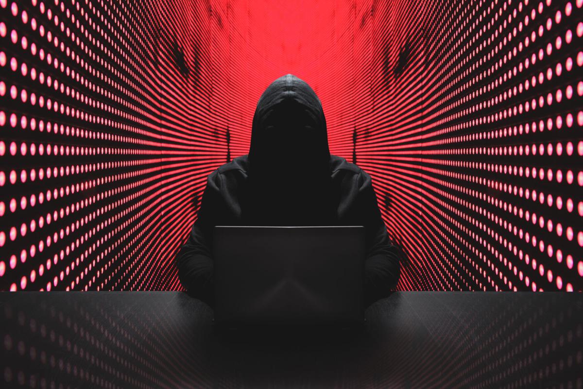 Anonymous hacker with laptop in front of binary code cyber security