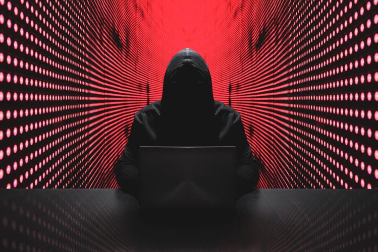 Anonymous hacker with laptop in front of binary code cyber security