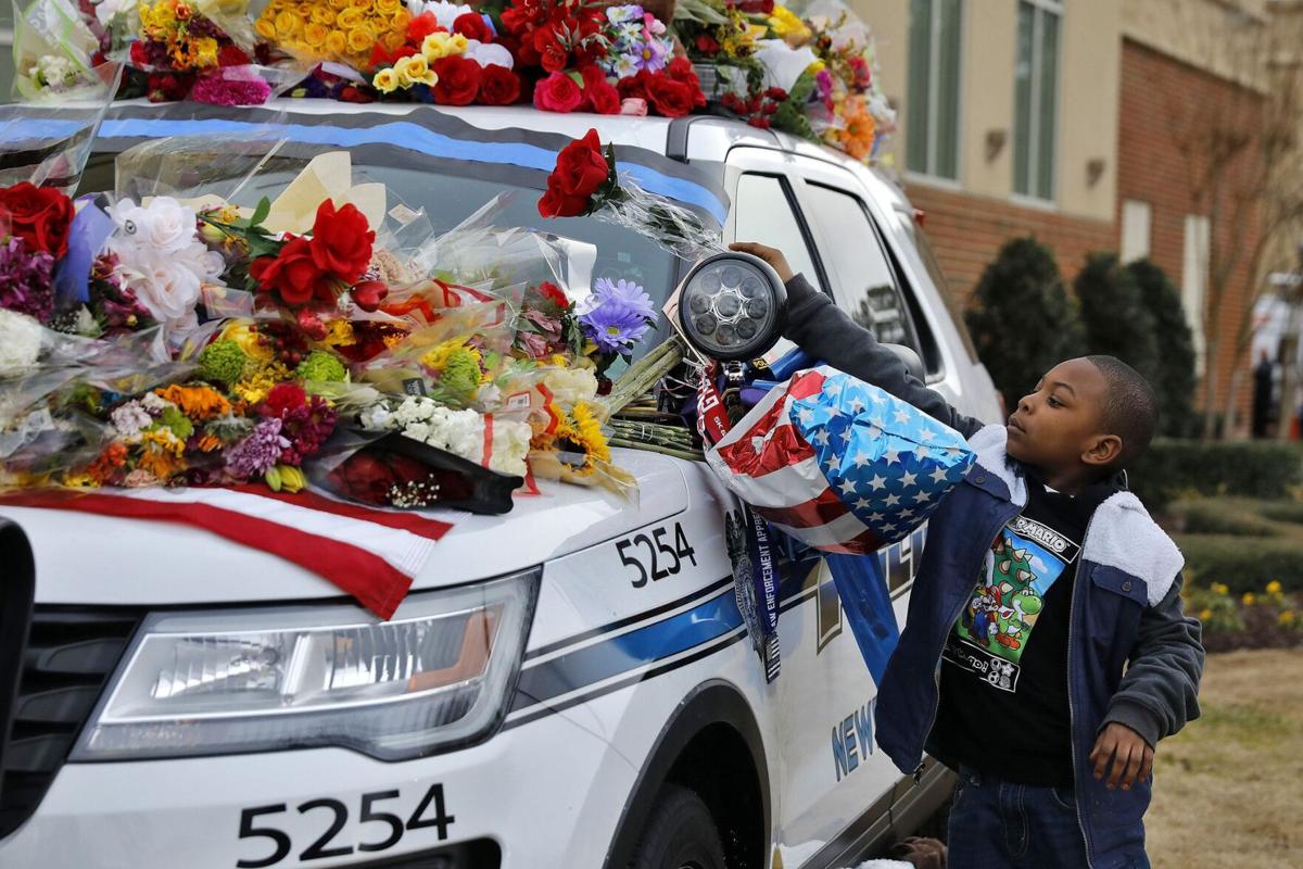 Marcus Allen places flowers on a memorial before the start of celebration of life service for Newport News police officer Katherine Thyne at Liberty Baptist Church in Hampton on Feb. 3, 2020. Officer Thyne died on Jan. 23, 2020 after being dragged by the car of a man who she and another officer were questioning.