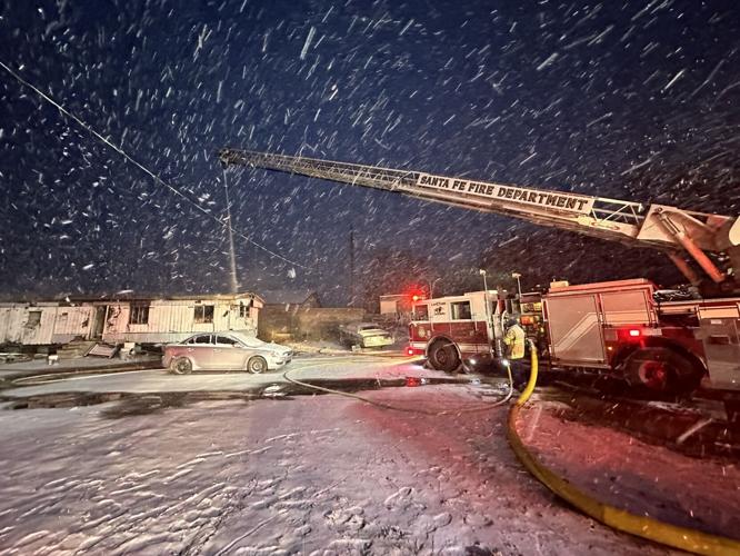 Santa Fe firefighters work in snow while responding to a mobile home fire