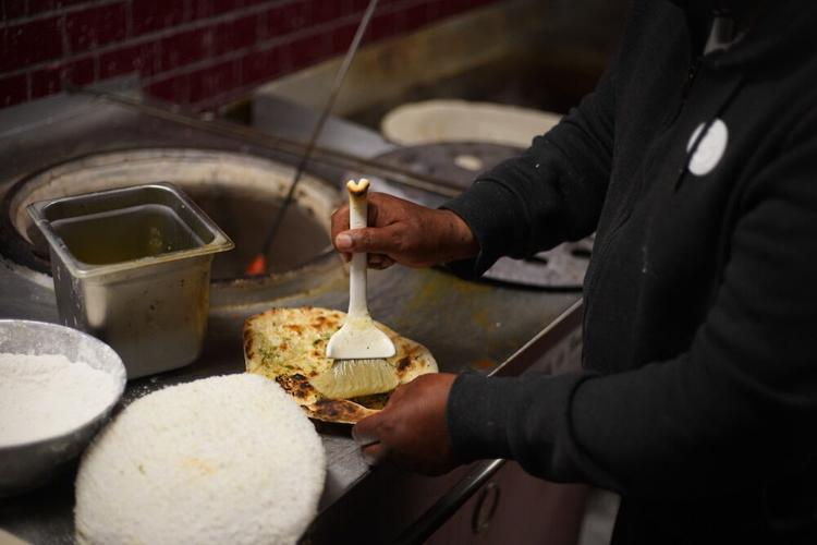 Homemade garlic naan is buttered.JPG