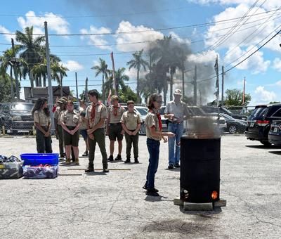 Darryl Grubbs, recently elected as Senior Patrol Leader of Boy Scout Troop 418, carefully drops one of the flags into the burn barrel at the Memorial Day ceremony.
