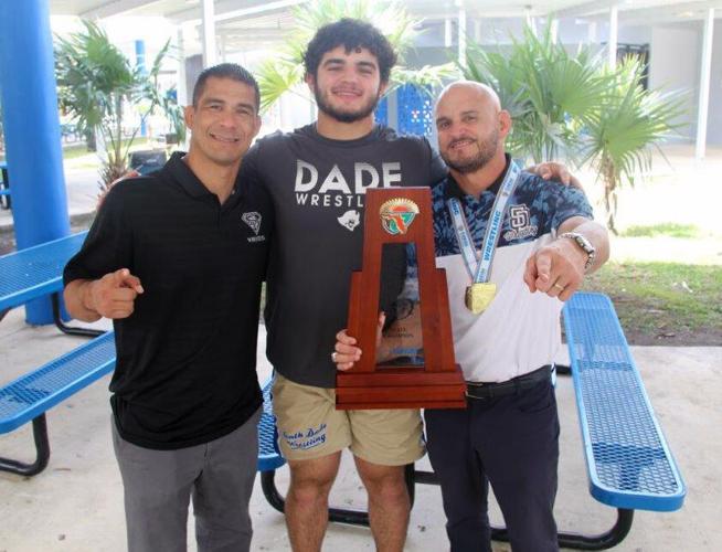Sawyer Bartelt (middle) one of the best high school wrestlers in the nation and the winner of a Florida state wrestling championship at 220 lbs, South Dade wresting Coach Victor Balmeceda (right) and  assistant coach Humberto Reyna (left), who  wrestled...