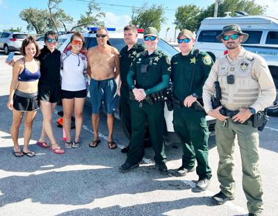 Deputies and officers pose with the rescued  paddleboarders after they made it back in safely.