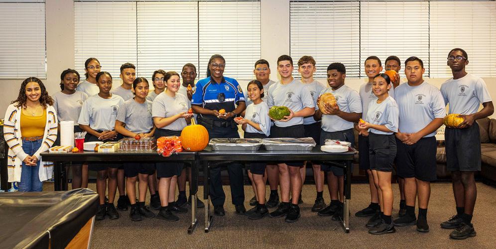 Homestead Community Policing Officer Shanell Wadley stands with the Student Explorers as they prepare to feast on the meal provided by Carline Camp.
