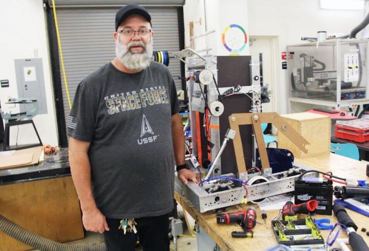 South Dade High School Teacher Shawn Waring stands in front of a robot used by the robotics class.