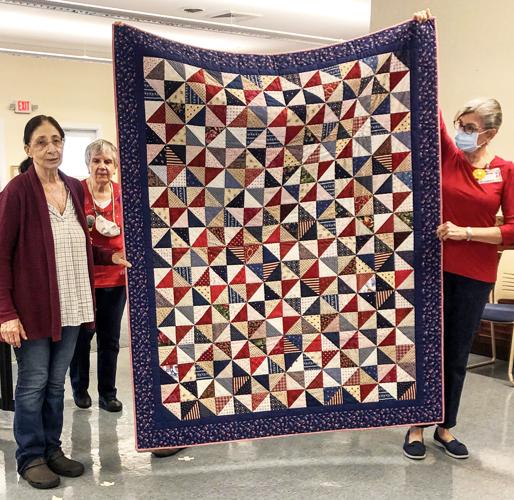Quilter Helen Demmie McKane accepts the quilt for Vietnam veteran Jose Adan with quilters Joyce Cotner and Linda Falls
