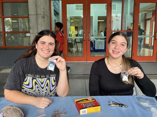 Karina Soria (left) and Yamaris Molina (right) display a STEM/Art project using rapidly germinating lima beans. Molina shows her “necklace” where the lima bean was already starting to germinate after only a couple of hours.