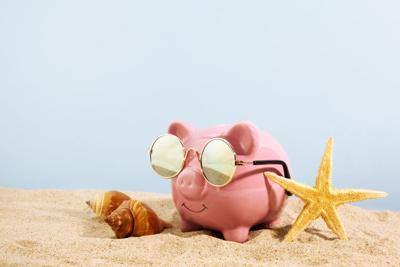 Pink piggy bank with sunglasses on the beach