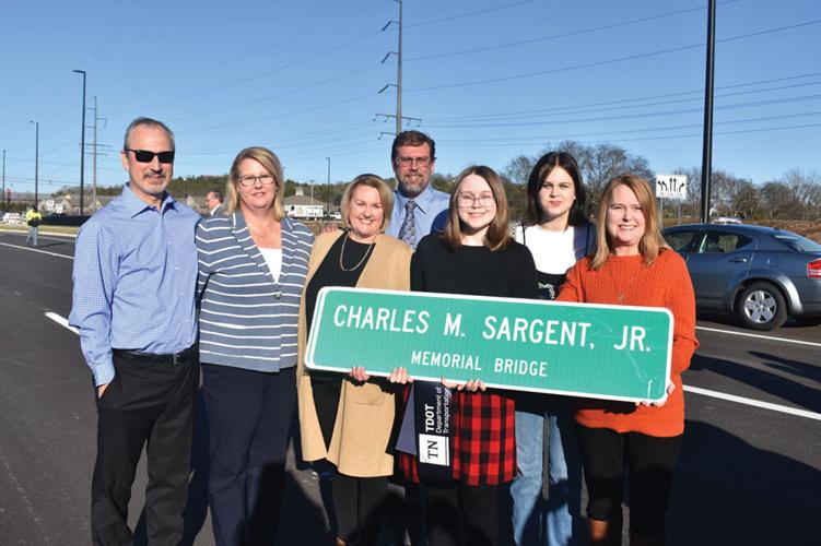 The family of Charles M. Sargent hold the new sign that will be placed on the Mack Hatcher extension bridge named in his honor