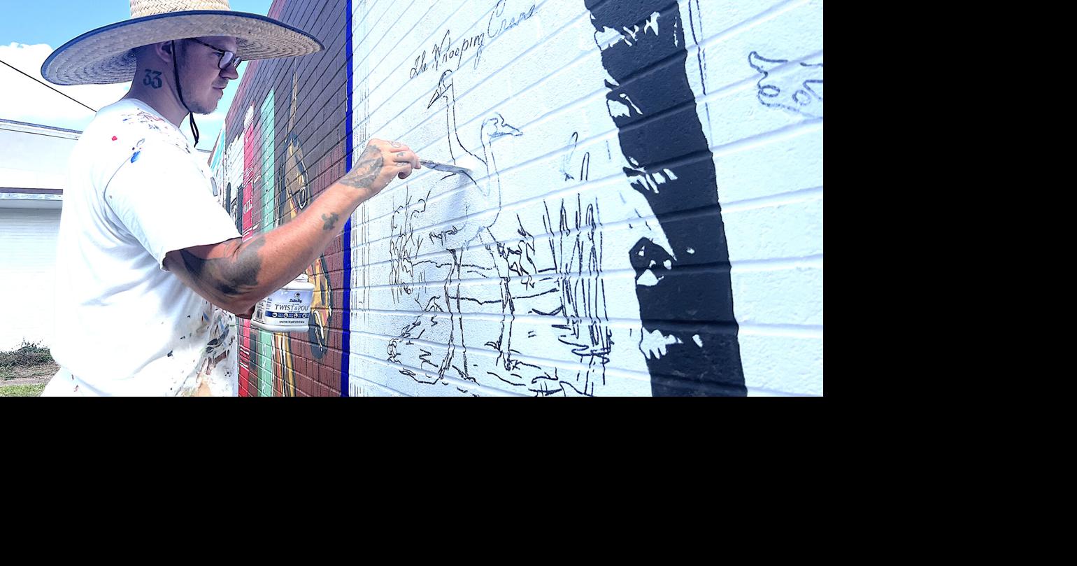 Artist honoring Refugio County with mural on wall at library