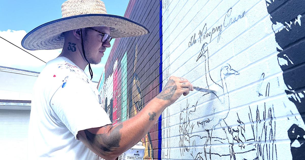 Artist honoring Refugio County with mural on wall at library