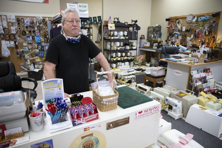 Shopkeeper making sewing machine repairs so others can make masks