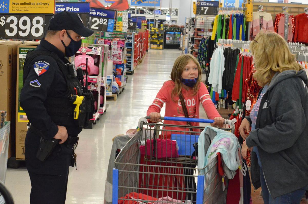 Officer Pope helps Hailey Settle (middle) and Michelle Settle shop for clothes during the annual Cops and Kids shopping program sponsored by the Iredell County Fraternal Order of Police.