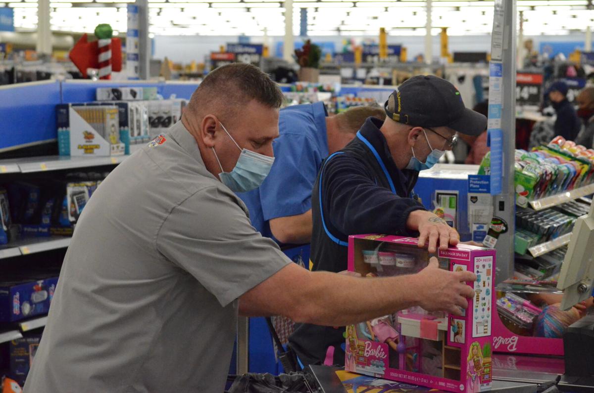 A member of the North Carolina Fraternal Order of Police Iredell County Lodge 10 helps bag items with a cashier from Walmart during the annual Cops and Kids shopping program sponsored by the Iredell County Fraternal Order of Police.
