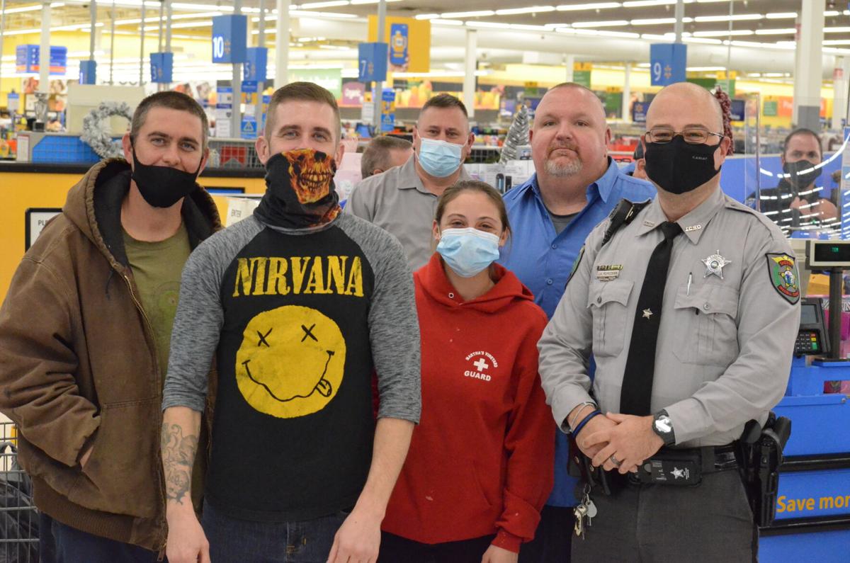 Deputy Jason Kohnstamm (left) and Rodney James (second from left) pose with a family during the annual Cops and Kids shopping program sponsored by the Iredell County Fraternal Order of Police.