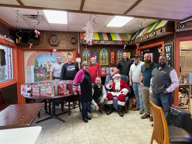 Jeff Smith, Robert Little, Anna Johnson, Mark Vaughn, Dru Schneeberger, Jimmy Trivette, Jeff Kerr, Paul Spencer, Philip Ostwalt, and Teross Young pose for a photo while serving meals on Christmas.