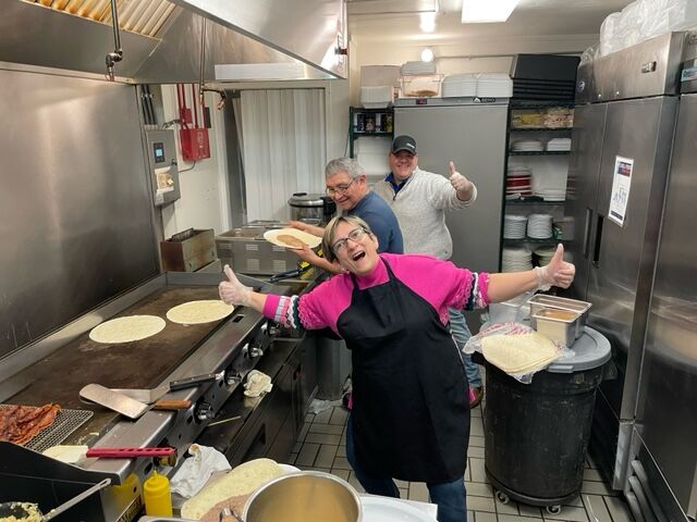 Ana Johnson, front, and other volunteers help cook a meal for local children on Christmas.