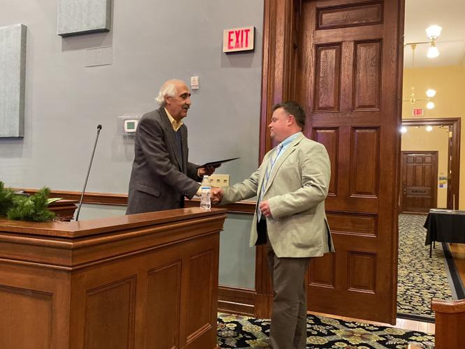 Mayor Costi Kutteh shakes hands with Brian Roberts as he presents the Finance Department with the Distinguished Budget Presentation Award from the Government Finance Officers Association during a city council meeting on Monday in Statesville.
