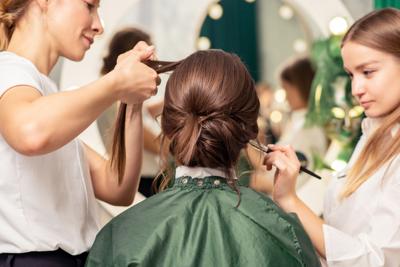Makeup artist and hairdresser preparing bride