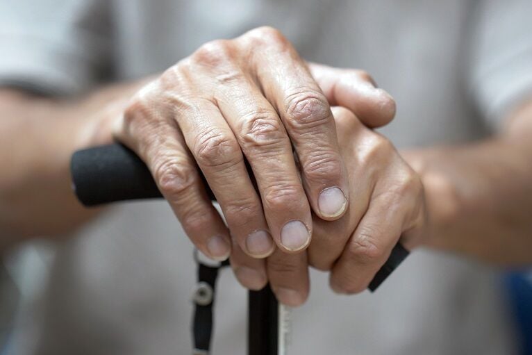 Hands of a senior man holding a cane