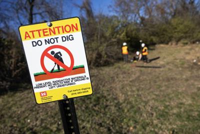 Contractors with the Army Corps of Engineers install signage along Coldwater Creek