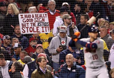 A sign referring to the Houston Astros cheating, is held by a fan during the Boston Red Sox game against the Houston Astros in Game 3 of the American League Championship Series at Fenway Park on Oct. 18, 2021, in Boston.