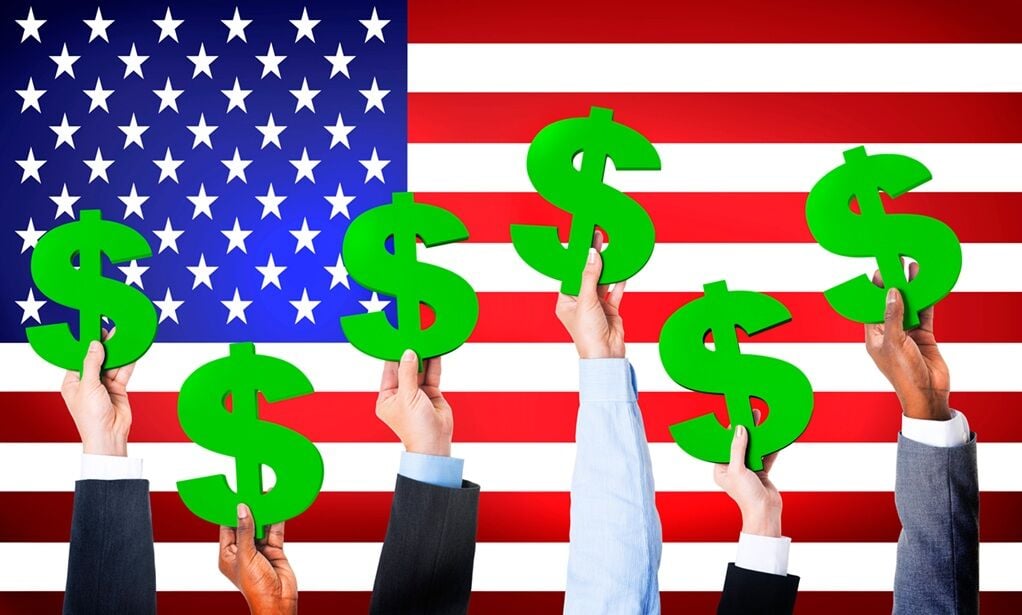 Multi-Ethnic Hands Holding Dollar Signs With Flag Of USA For The Background.