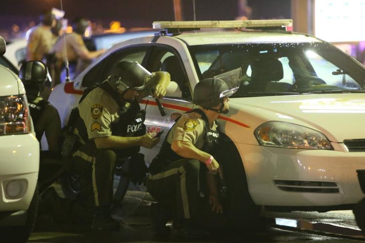 Police take cover as shots are fired during a ferguson protest