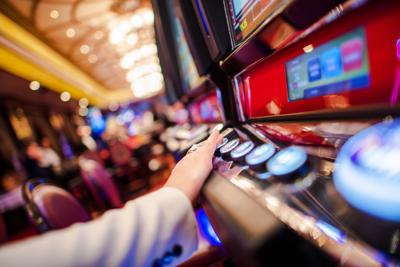 Casino Slot Video Games. Woman Playing Video Slot in the Casino. Hand on Betting Button Closeup Photo.