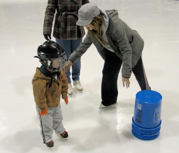 Baby steps with a blue bucket at a Granite City ice rink