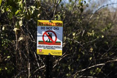 Contractors with the Army Corps of Engineers install signage along Coldwater Creek