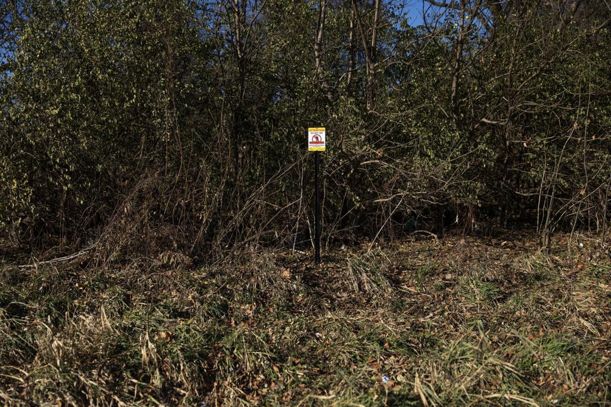 Contractors with the Army Corps of Engineers install signage along Coldwater Creek